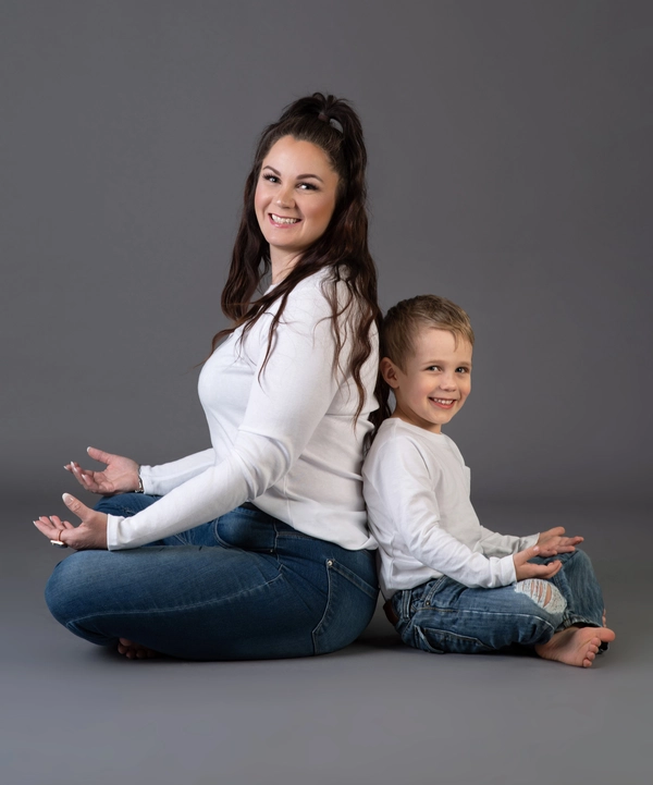 A parent sits on a plush rug, reading a children's book titled "One, Two, Three, Meditate with Me" to a young child.
